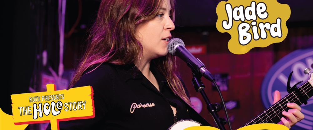 Jade Bird playing guitar and singing into a microphone