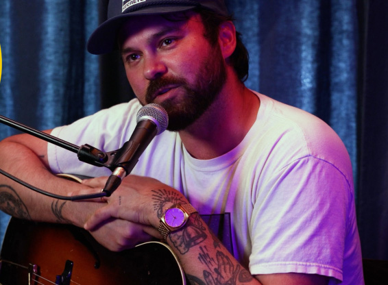 Shakey Graves with his guitar at a mic